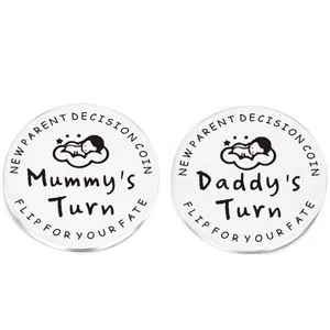 Detail of baby decision coins showing Daddy's and Mummy's Turn engraved on steel