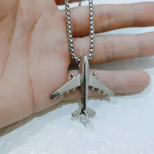 Dettaglio ravvicinato di un ciondolo a forma di aereo d'argento su una catena a scatola