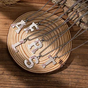 Macro detail of silver baseball letter pendants with red stitching on a wooden stand