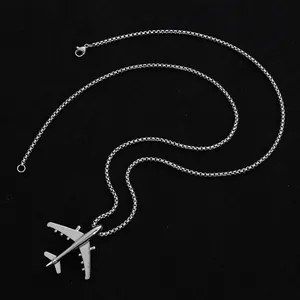 Dettaglio macro del ciondolo aereo d'argento con catena box su sfondo nero intenso