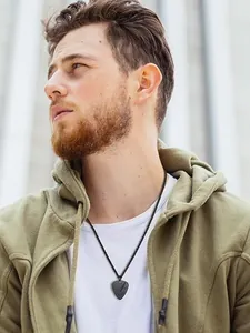Dettaglio del ciondolo a plettro nero con motivo a chitarra su una collana di corda intrecciata