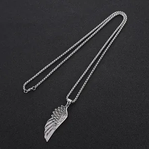 Collier vintage avec pendentif aile en acier inoxydable sur un fond noir texturé
