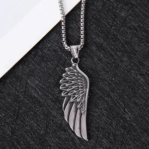 Détail du pendentif aile vintage sur une chaîne à maillons carrés aux textures nettes