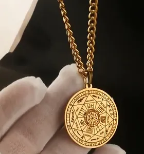 Detalle del colgante de sello de arcángeles en acero dorado sujeto en la mano