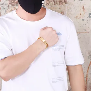 Gros plan d'un bracelet gourmette en acier doré avec plaque d'identité sur poignet masculin