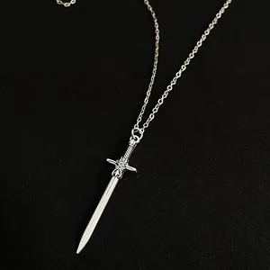 Collier épée argentée minimaliste avec motif de croix sur fond texturé noir