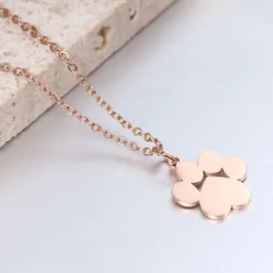 Dettaglio del ciondolo a zampa in oro rosa su catena a O con sfondo in pietra naturale