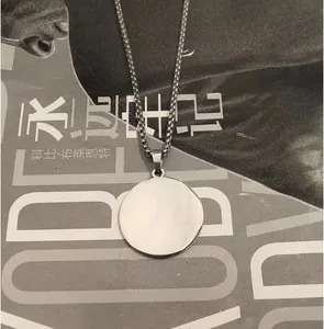 Pendentif rond en acier inoxydable poli sur chaîne box posé sur un magazine
