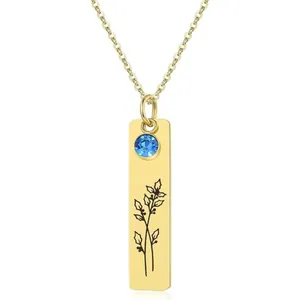 Detail of gold rectangular pendant with blue birthstone and minimalist flower engraving
