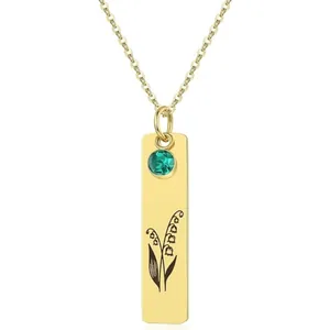 Detailed view of golden rectangle pendant with lily of the valley and green gem inlay