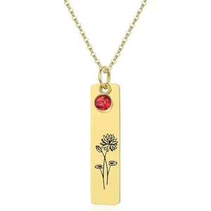 Macro detail of gold floral engraved pendant with a red gemstone on a simple cable chain
