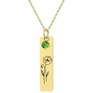 Detailed macro view of a gold rectangular pendant with green gemstone and poppy etching