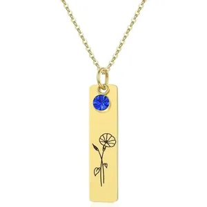 Macro view of gold bar pendant necklace with blue gemstone and flower engraving