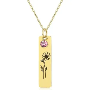 Macro view of gold rectangle pendant with pink gemstone and engraved daisy flower