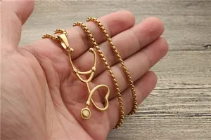 Detailansicht der herzförmigen Stethoskop-Halskette in Gold-Finish, in der Hand gehalten