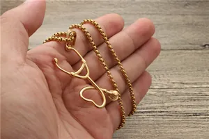 Detailaufnahme goldene Stethoskop-Halskette mit Herzanhänger auf Holzgrund-Hintergrund