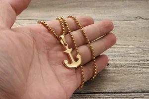 Gros plan d'un pendentif ancre doré avec chaîne à maillons montrant la taille réelle