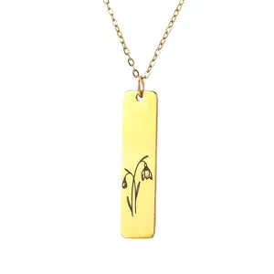 Macro view of gold rectangular stainless steel pendant with black flower engraving