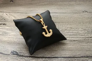 Pendentif ancre dorée poli avec chaîne à billes sur un coussin de bijoux en cuir noir
