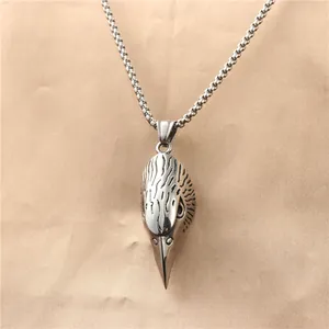 Macro shot of silver eagle head pendant in polished stainless steel on a beaded chain