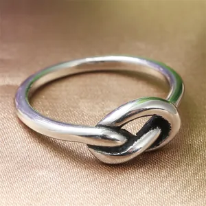 Macro di anello a nodo in acciaio lucido argento su sfondo di raso dorato