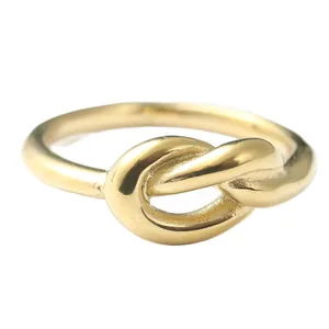 Dettaglio macro dell'anello a nodo in acciaio dorato con finitura lucida a specchio