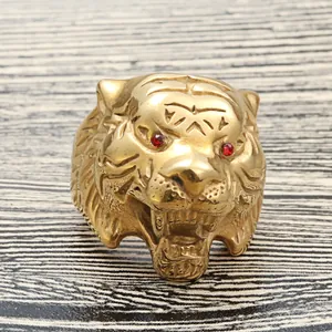 Punk style gold tiger head ring with red rhinestone eyes on a wooden background