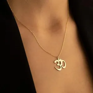 Elegant gold stainless steel Om pendant necklace for women worn with a black suit jacket