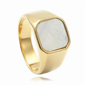 Detalle de un anillo punk de acero dorado con incrustación de nácar blanco y banda ancha