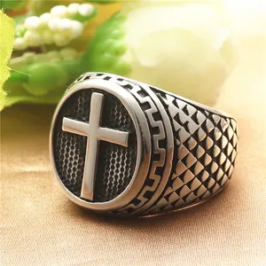 Close-up of vintage stainless steel signet ring featuring a 3D cross and geometric patterns