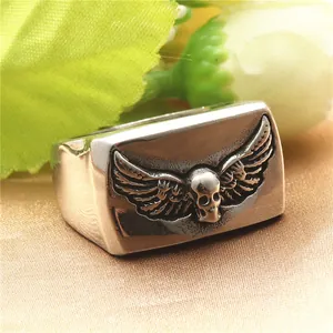 Detail view of vintage steel skull ring with wings on premium champagne silk fabric