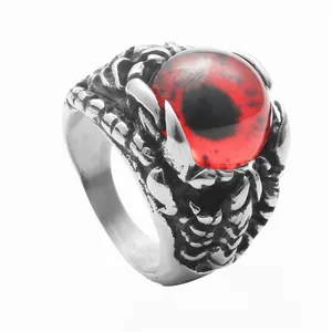 Macro detail of punk dragon claw ring in stainless steel with a red glass evil eye