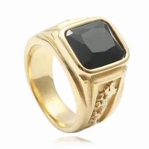 Close-up of men's gold signet ring featuring a large square black stone and embossed side