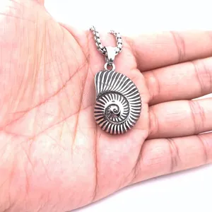 Colgante nautilus vintage de acero inoxidable plateado sostenido en la palma de mano