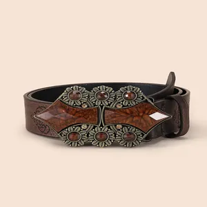 Ceinture bohème en similicuir marron avec boucle florale vintage et pierres sur fond beige