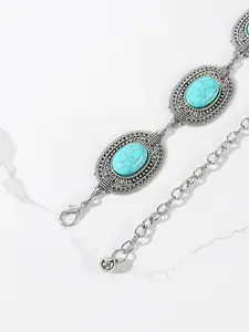 Detailed view of bohemian style silver chain belt with turquoise stones and floral engravings