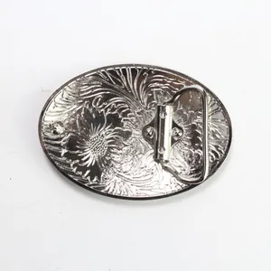 Detail van achterkant zilveren riemgesp met bloemenreliëf en metalen sluiting