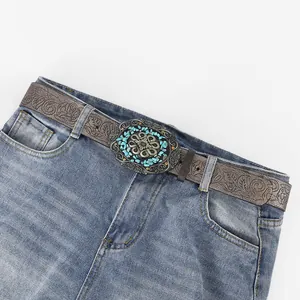 Bohemian vintage waist belt with turquoise embossed metal buckle on blue jeans