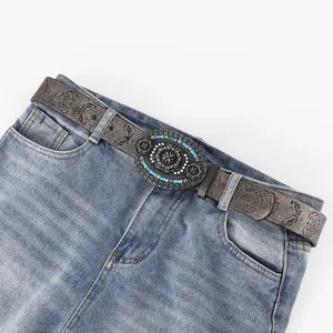 Cintura vintage in pelle goffrata con fibbia di gemme blu su jeans in denim