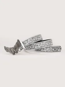 Dettaglio cintura in pelle bianca con fibbia ad aquila e motivi floreali vintage neri