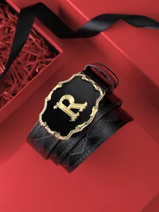 Détail d'une ceinture en cuir avec boucle dorée en R dans un coffret cadeau de luxe