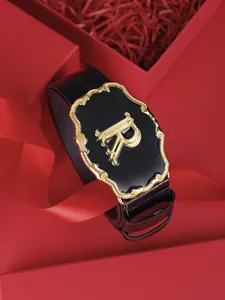 Détail de la boucle de ceinture noire avec la lettre R dorée dans un coffret cadeau rouge