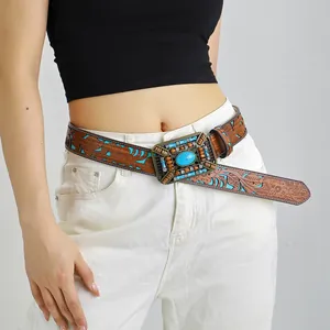 Boho vintage leather belt with floral embossing and turquoise buckle on white jeans