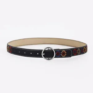 Détail de la ceinture en cuir noir avec broderie losange colorée et boucle ronde argentée
