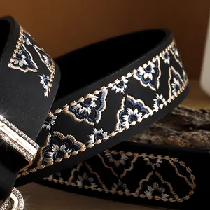Close-up of floral embroidery on black leather belt with rhinestone-studded buckle