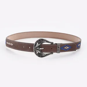 Close-up of vintage belt with blue floral embroidery and silver engraved buckle