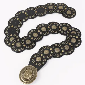 Detail van vintage westernriem met zwarte ronde leren patches en koperen bloemengesp