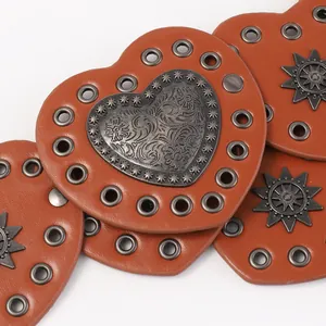 Detail of vintage heart-shaped brown leather belt with metal eyelets and star studs