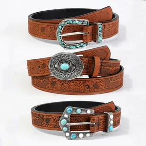 Detail of bohemian embossed leather belts with turquoise buckles and floral patterns
