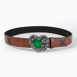 Detailed view of silver heart buckle with green gemstone on embossed brown leather belt
